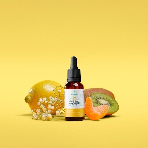 BEAUTÉNIUM Serum bottle with a dropper surrounded by lemon kiwi and orange slices on a bright yellow background